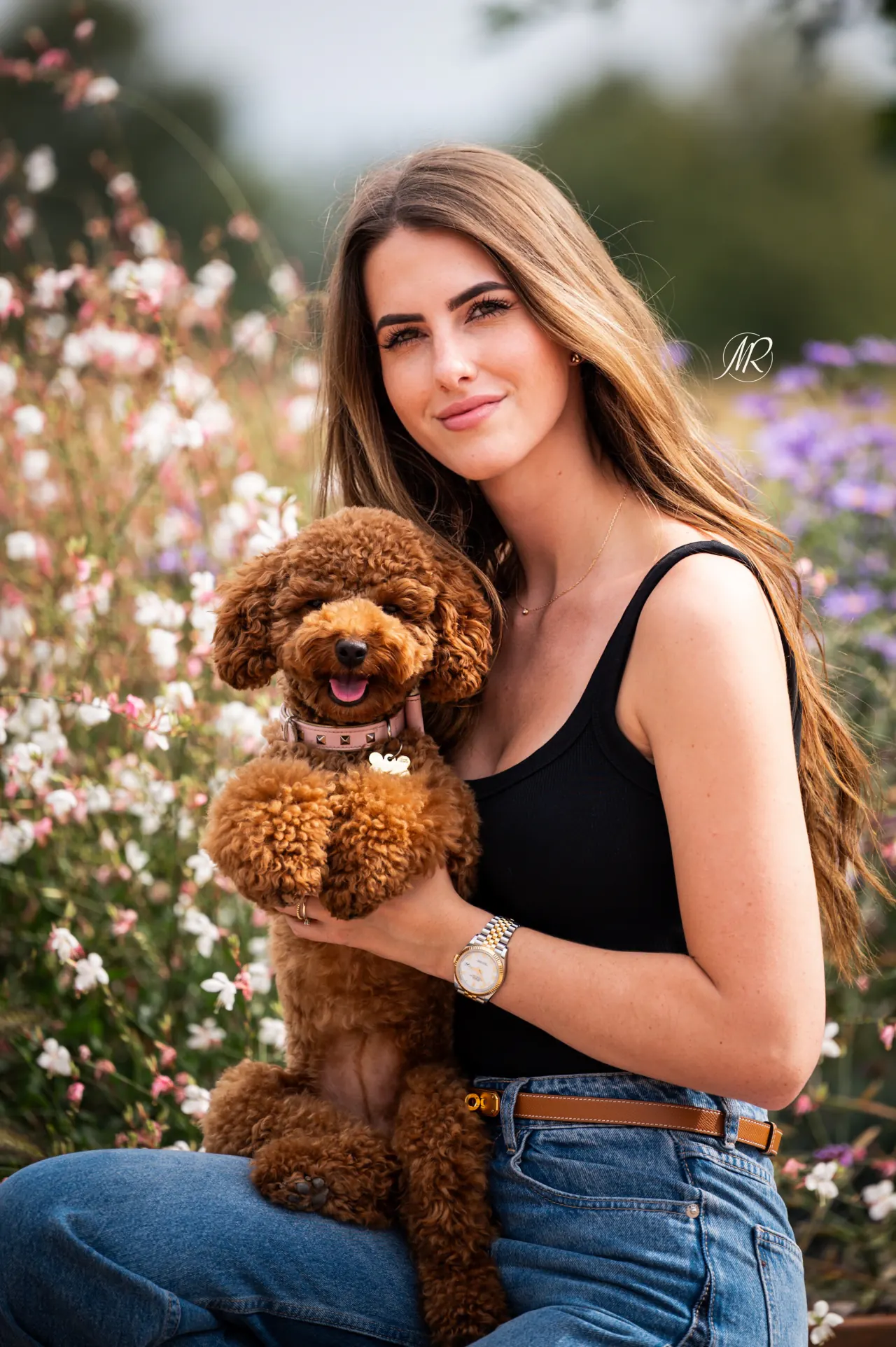 Rode toypoodle tussen bloemen met zijn baasje